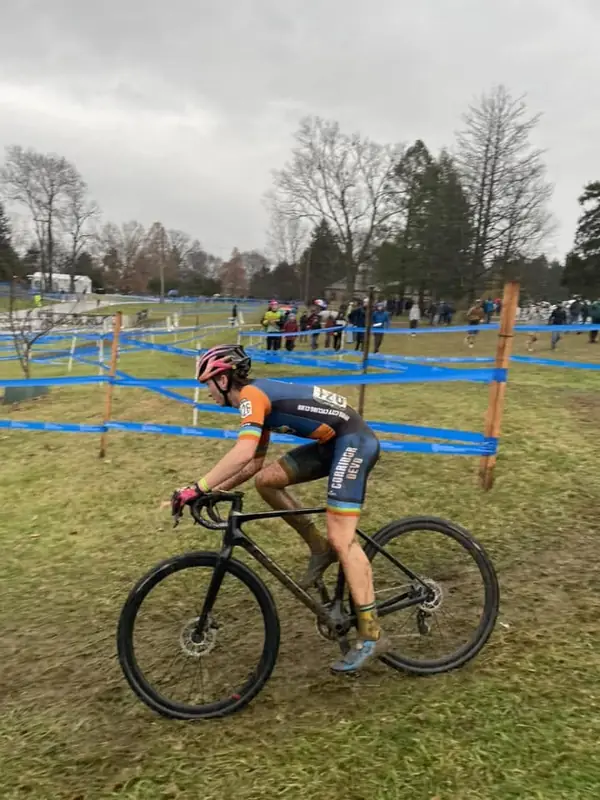 A rider in a Corridor Devo kit grinding through a muddy grass corner past the tape.